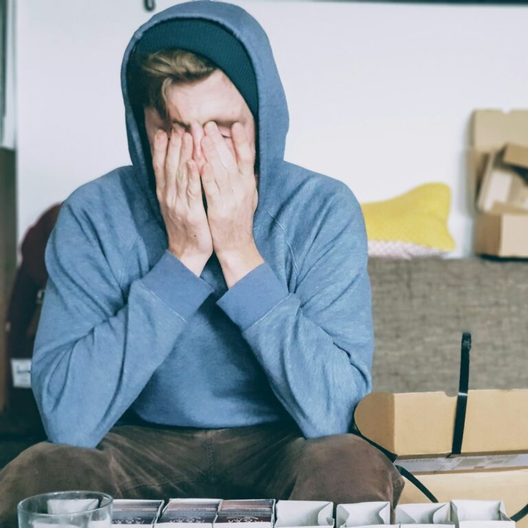 man covering face with both hands while sitting on bench